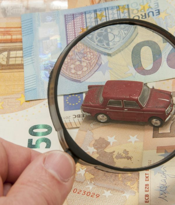 Magnifier finding a car on euro banknotes background, the concept of car valuation